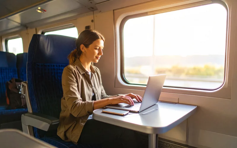 Femme utilisant un MacBook Air M4 dans un train, parfait pour travailler en mobilité